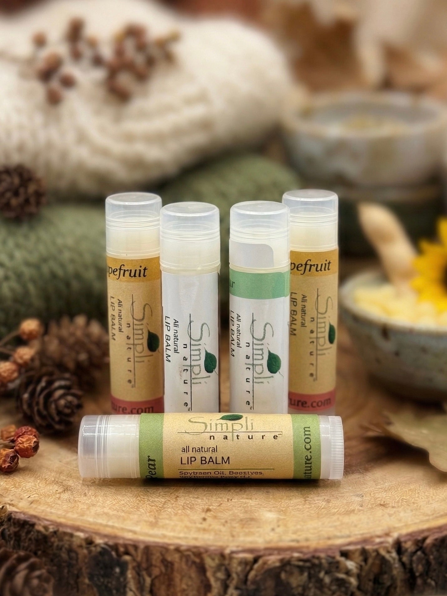 Collection of lip balm tubes on a wooden surface with natural elements in the background